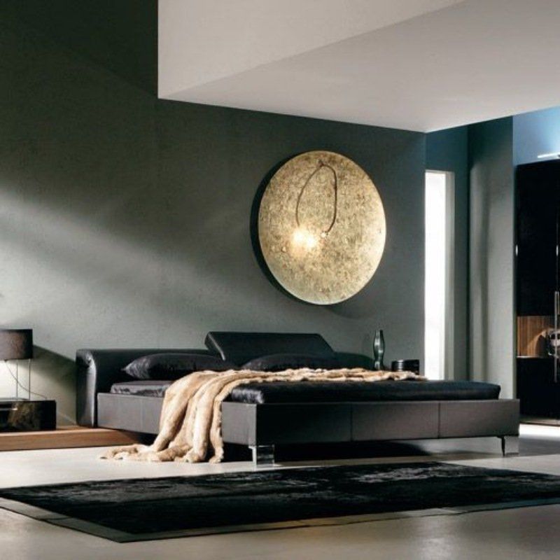 Camera da letto nera con letto, grande quadro dorato sulla parete e tappeto nero.