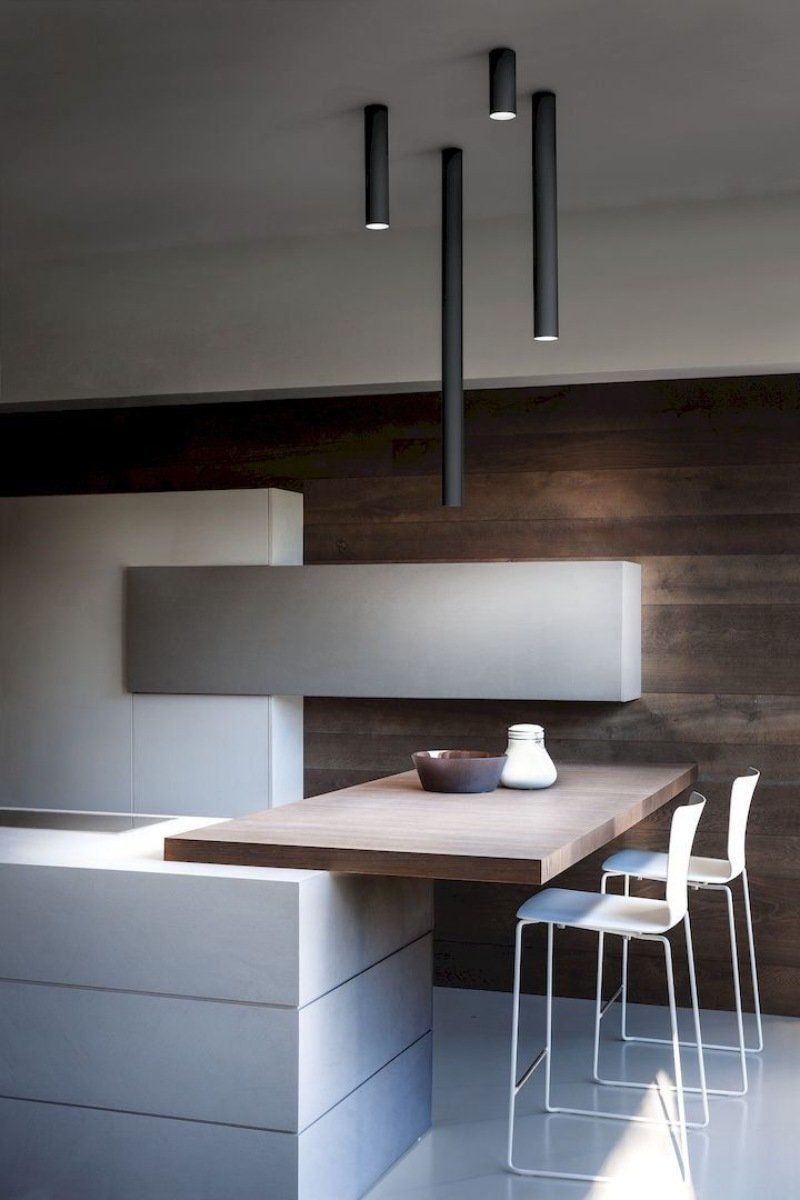 Cucina moderna con parete decorativa in legno scuro, isola bianca e lampade a sospensione.