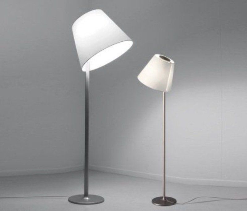 Due moderne lampade da terra con paralumi bianchi inclinati su pali in metallo grigio, che proiettano luce.