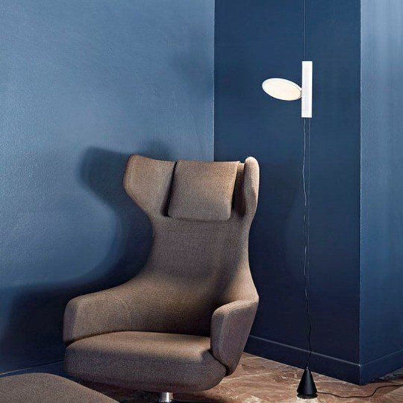 Poltrona grigia accanto alla parete blu, lampada da parete bianca.