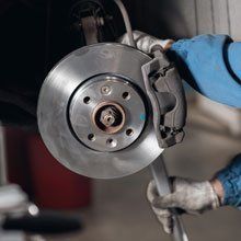 A person is fixing a brake disc on a car with a wrench.
