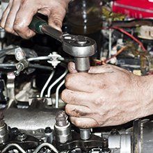 A man is working on a car engine with a wrench.