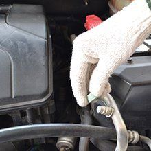 A person wearing gloves is working on a car engine.