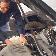A man is working on the engine of a car with the hood open.