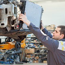 A man is working on the radiator of a car in a garage.
