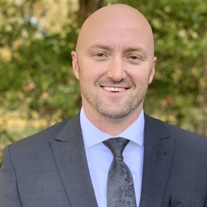 A bald man in a suit and tie is smiling for the camera.