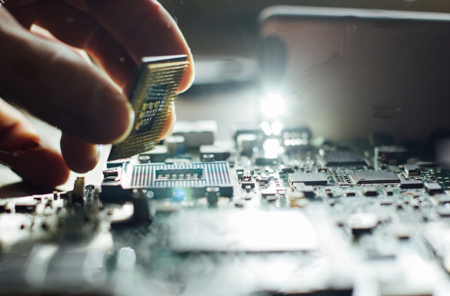A person is holding a cpu on top of a motherboard.