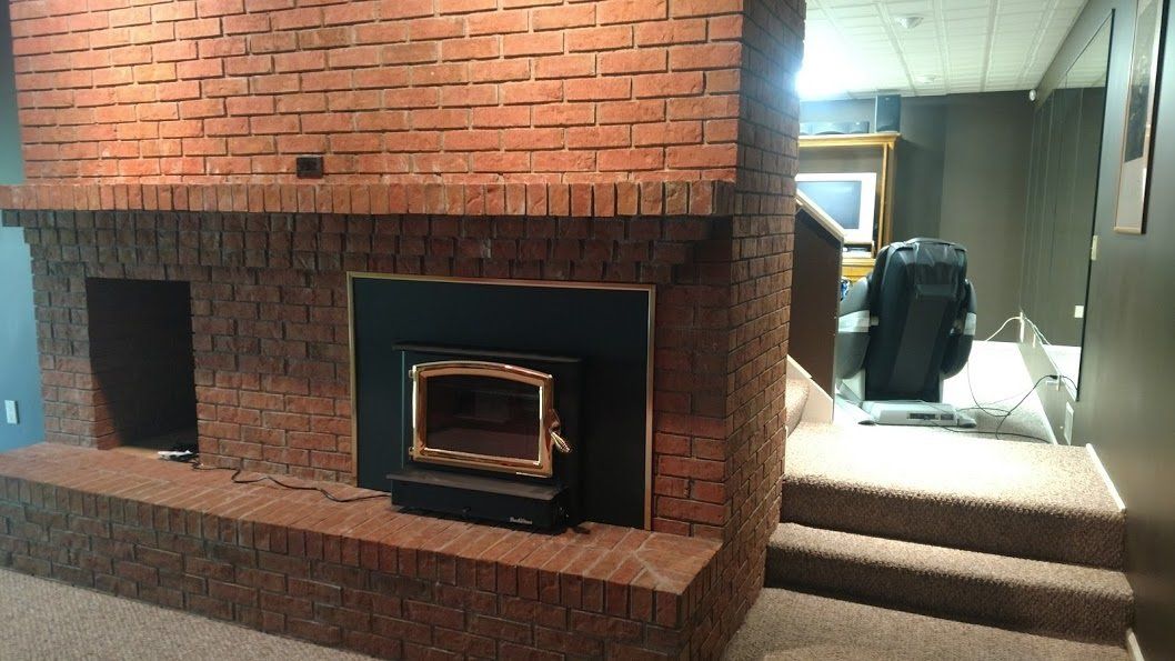 Brick fireplace with a black insert and gold trim. A step leads into a room.