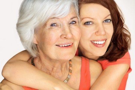 A young woman is hugging an older woman.
