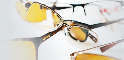 Three pairs of glasses are stacked on top of each other on a white surface.