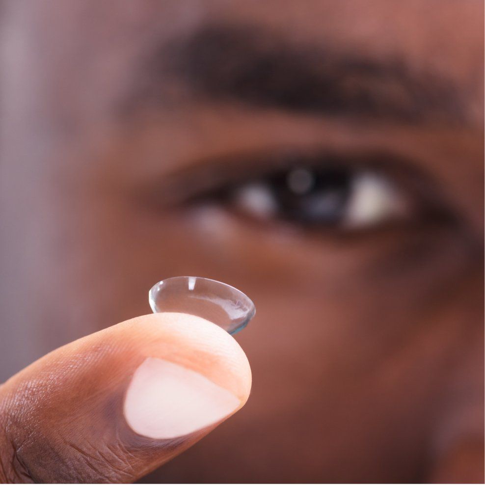 A close up of a person holding a gas permeable contact lens on their finger
