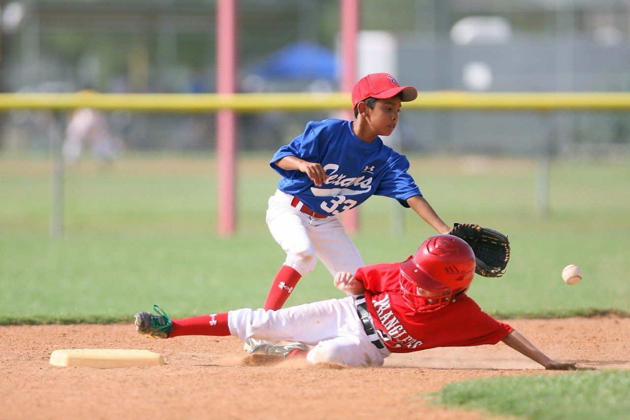 Two young boys are playing baseball on a field.