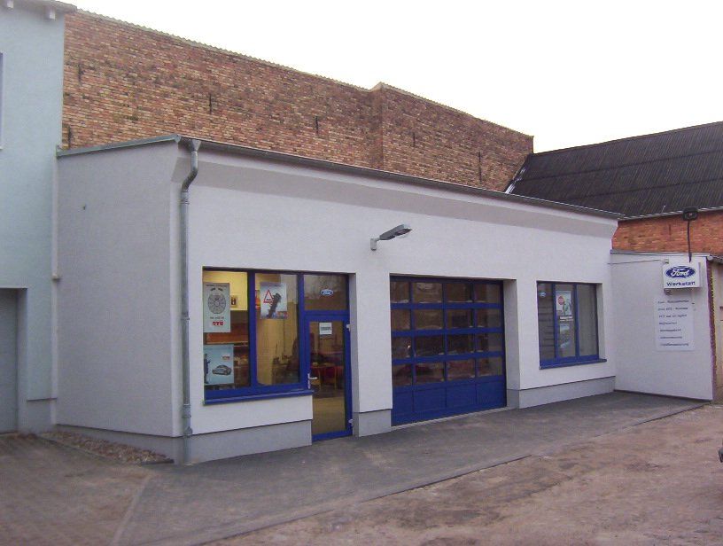 A white building with a blue garage door and a sign that says ford