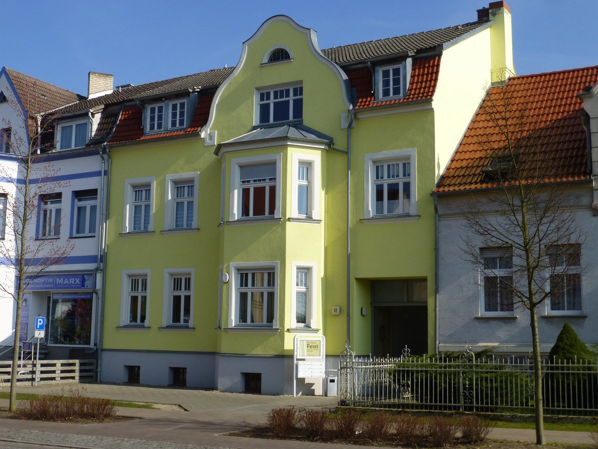 A yellow building with a red tile roof is next to a white building