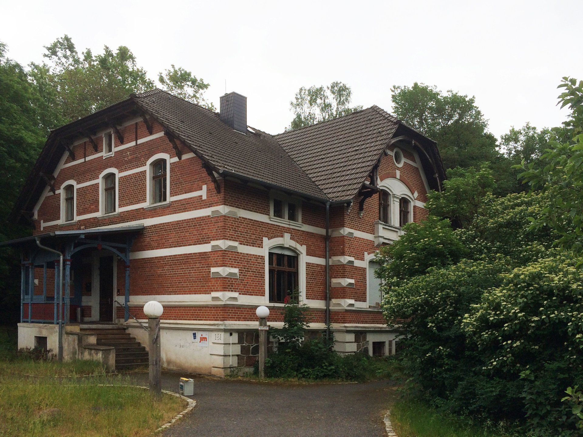 A large brick house is surrounded by trees and grass