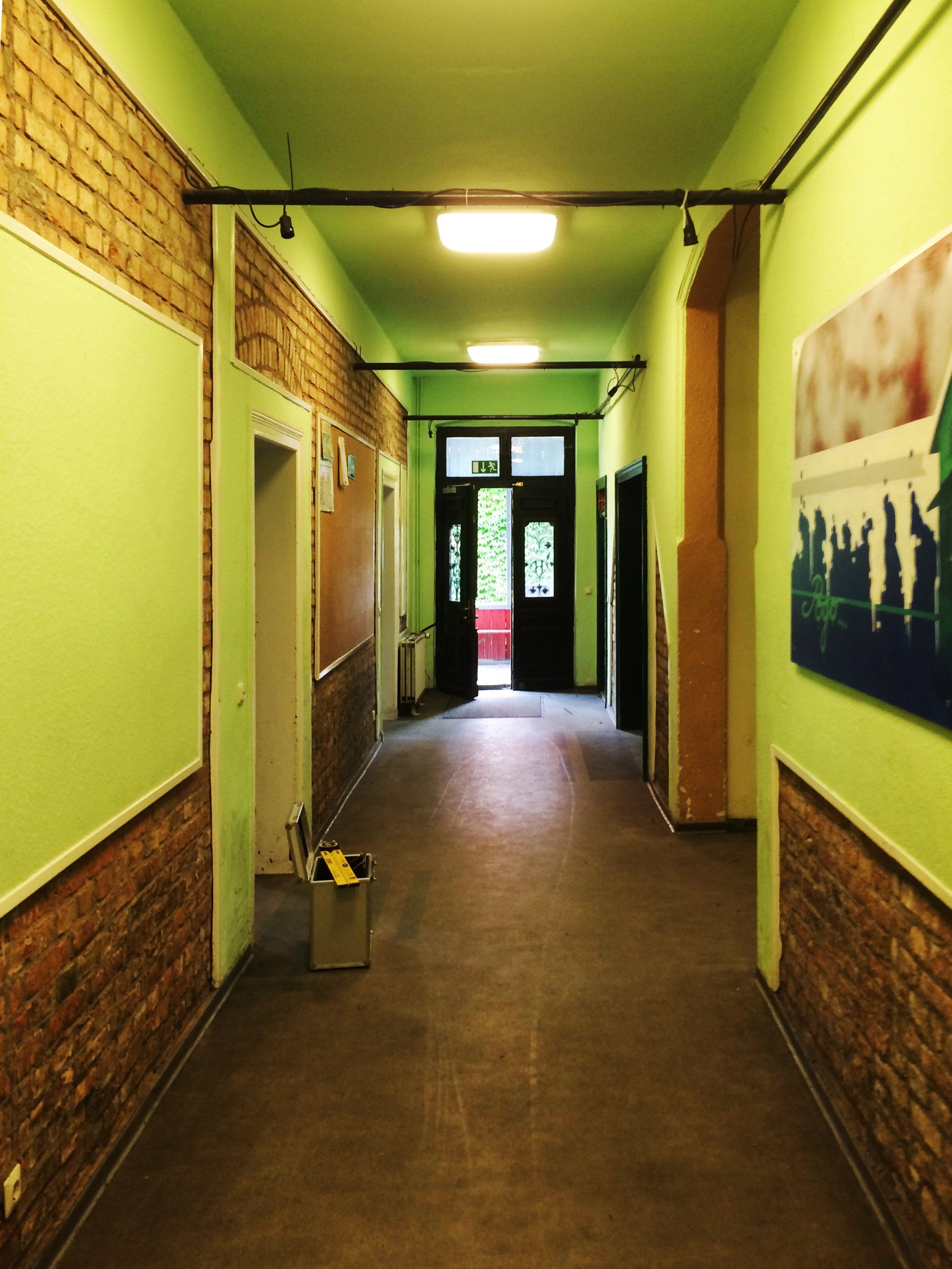 A long hallway with green walls and brick walls