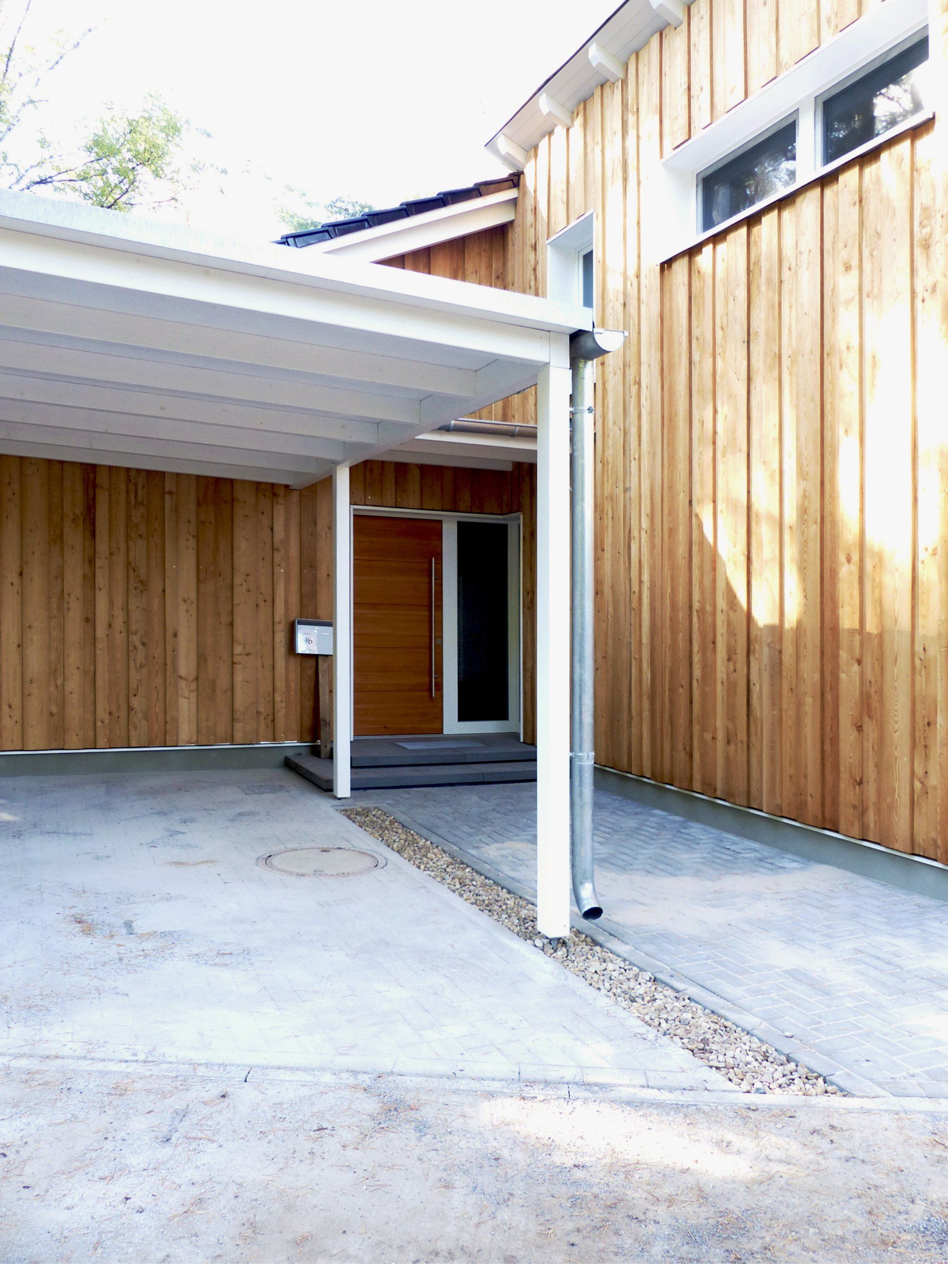 A carport is attached to the side of a wooden house.