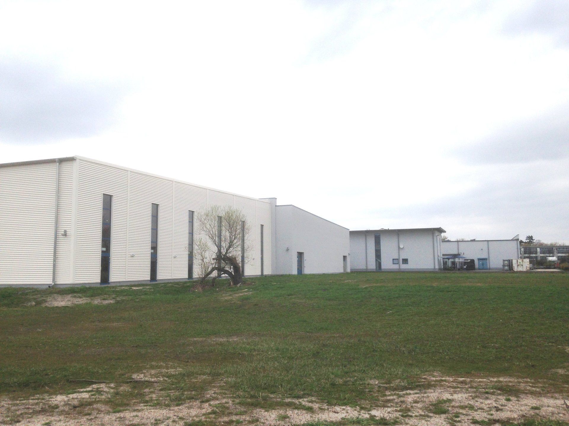 A large white building is in the middle of a grassy field