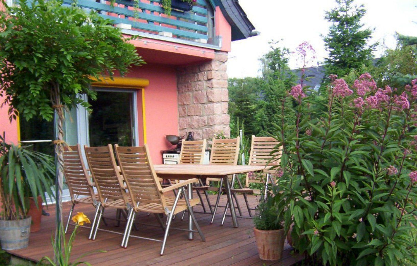 A table and chairs on a deck in front of a pink house