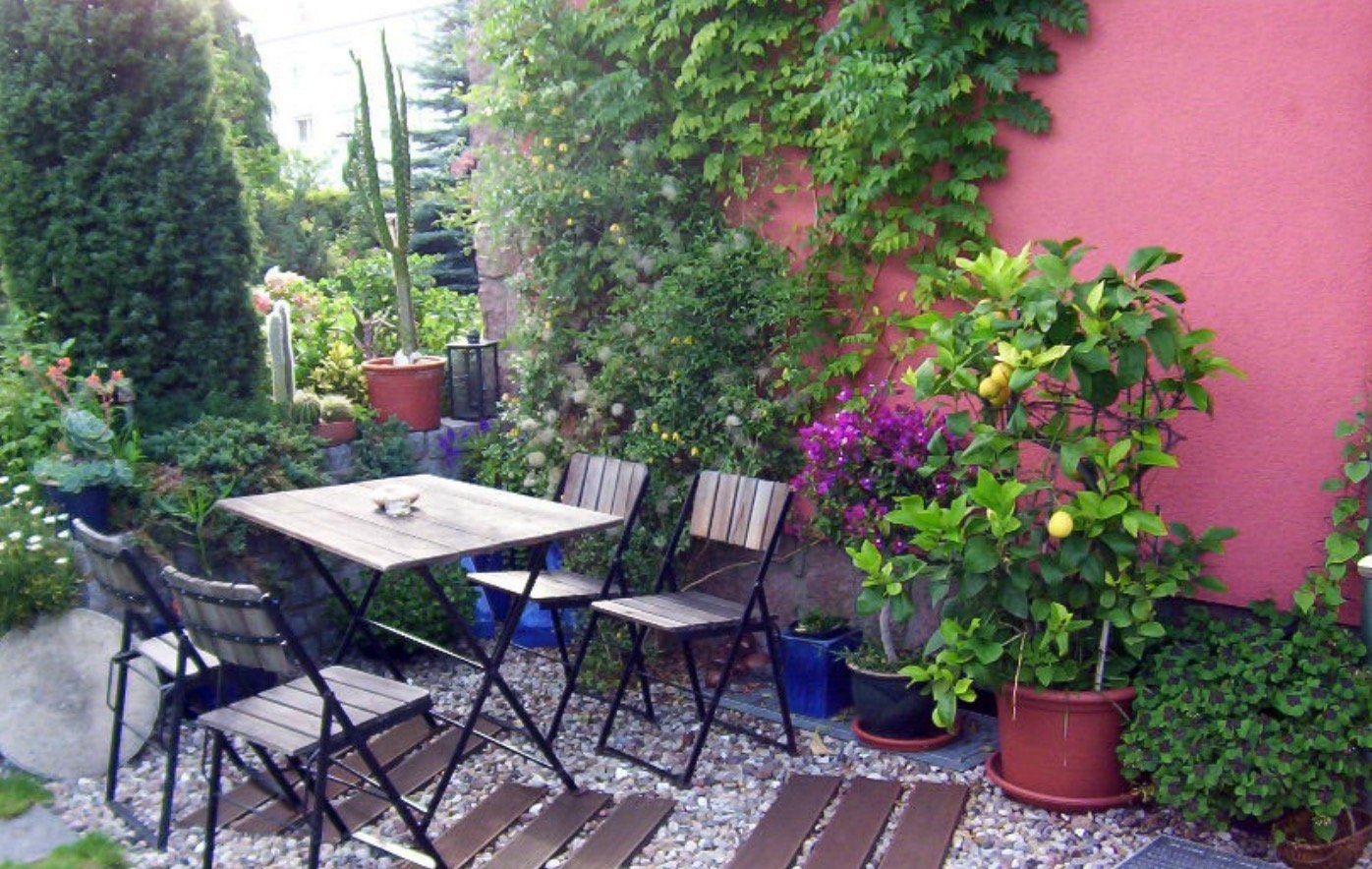 A patio with a table and chairs in front of a pink wall.