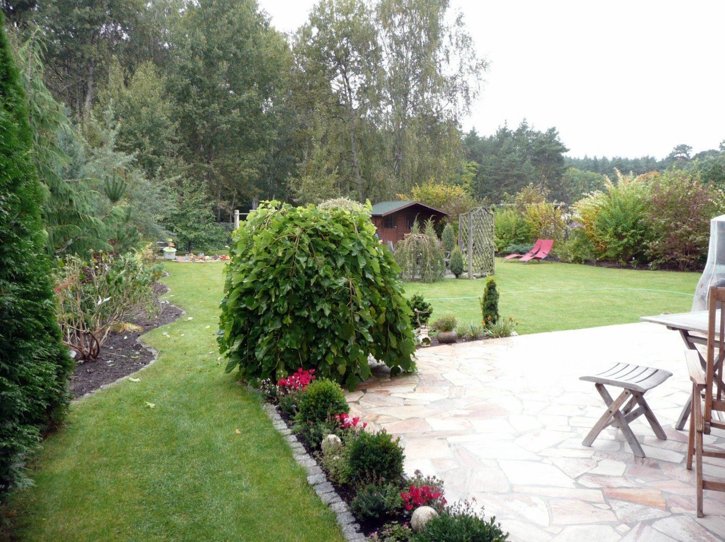 A patio with a table and chairs in a garden