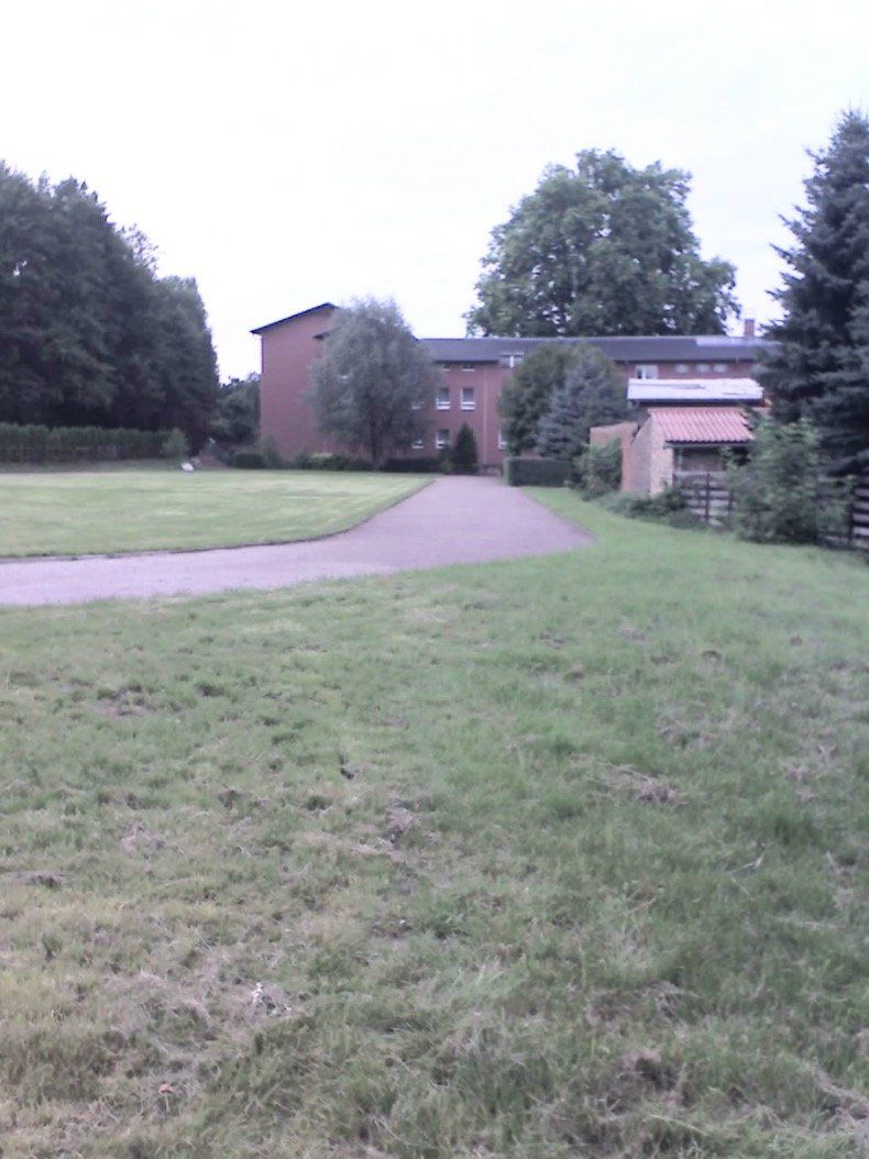 A grassy field with a brick building in the background