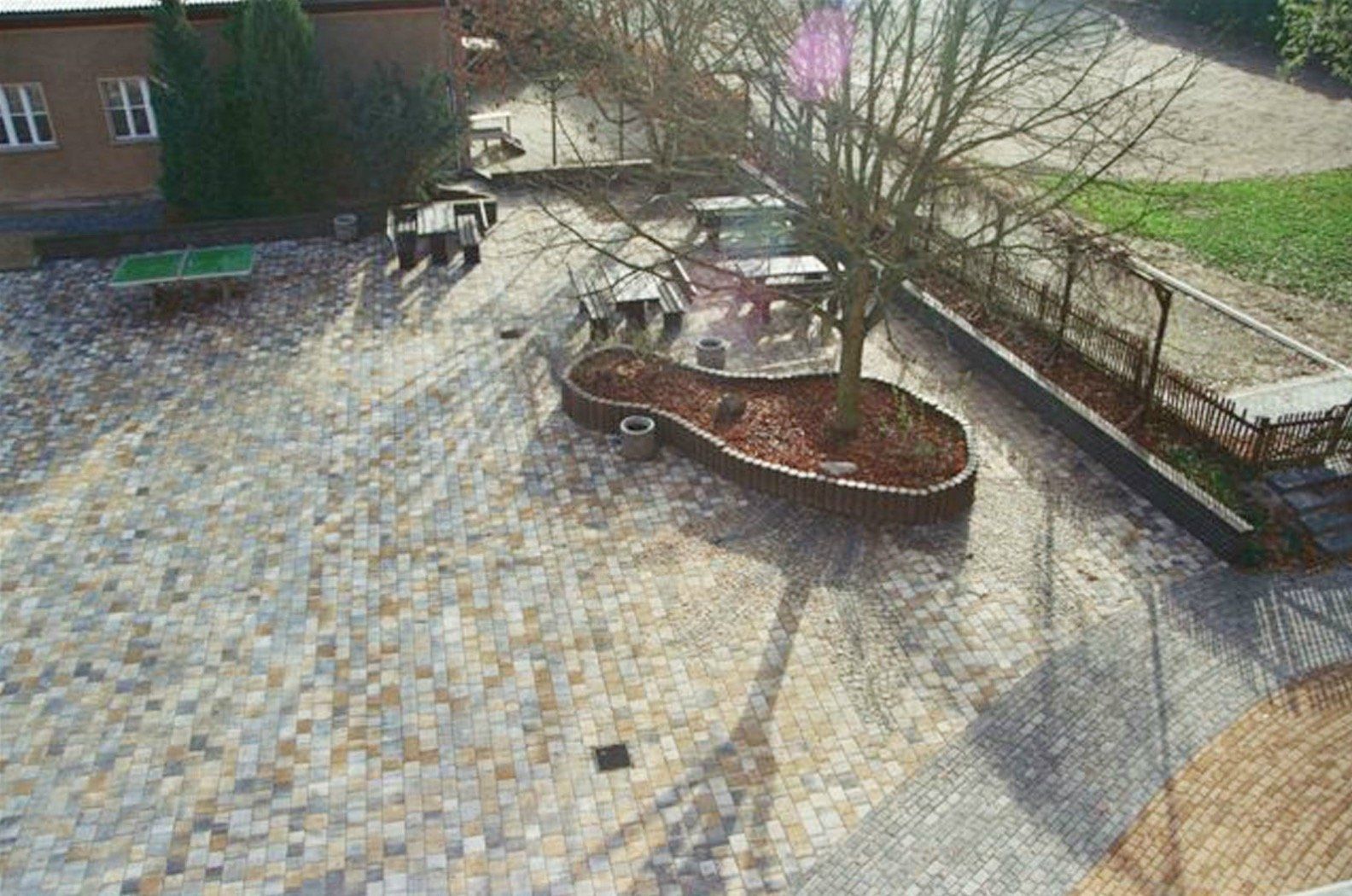 An aerial view of a patio with tables and chairs and a tree in the middle.