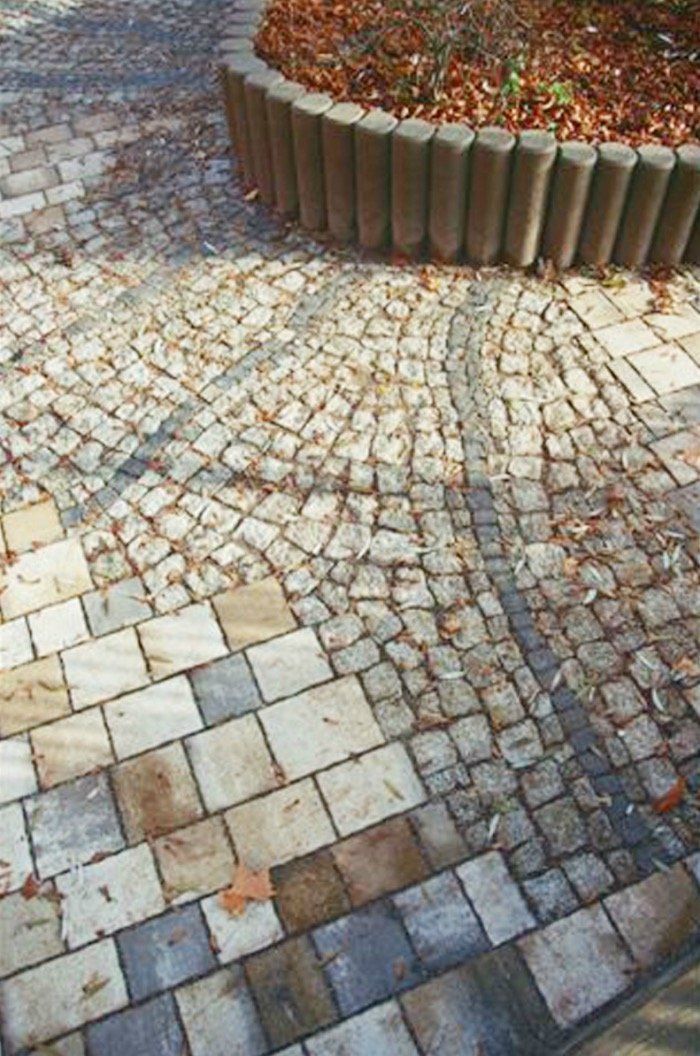 A brick walkway with a planter in the middle of it.