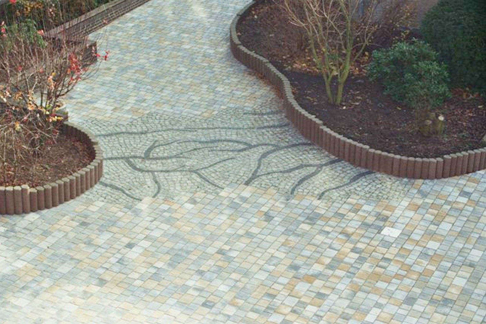 An aerial view of a brick driveway with a garden in the background.