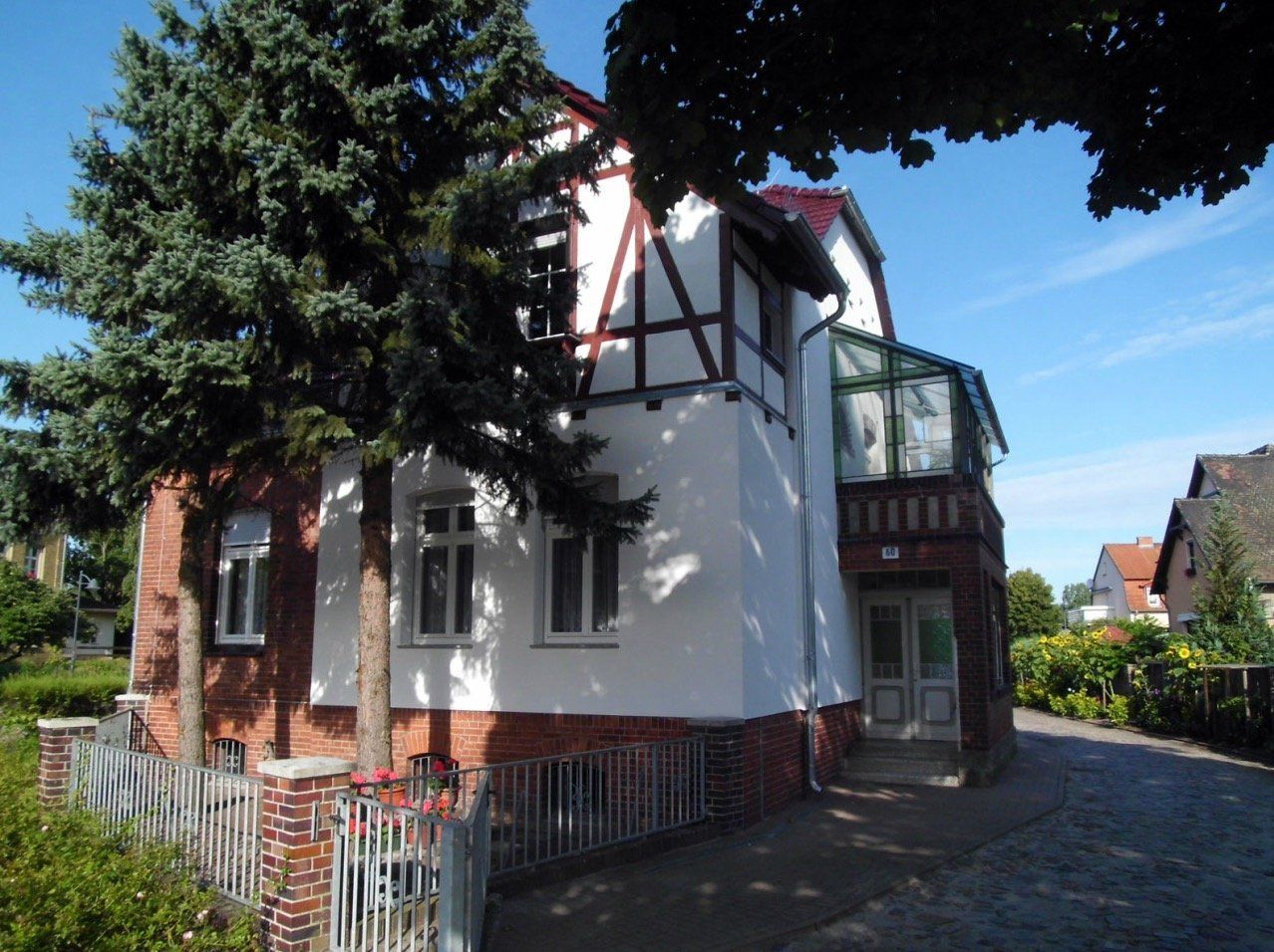 A white house with a red roof is surrounded by trees