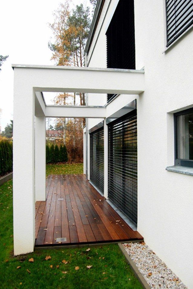 A white house with a wooden deck and sliding glass doors.