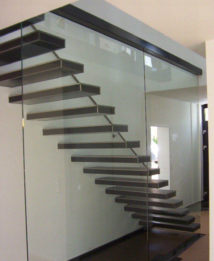 A staircase with a glass railing is in a room