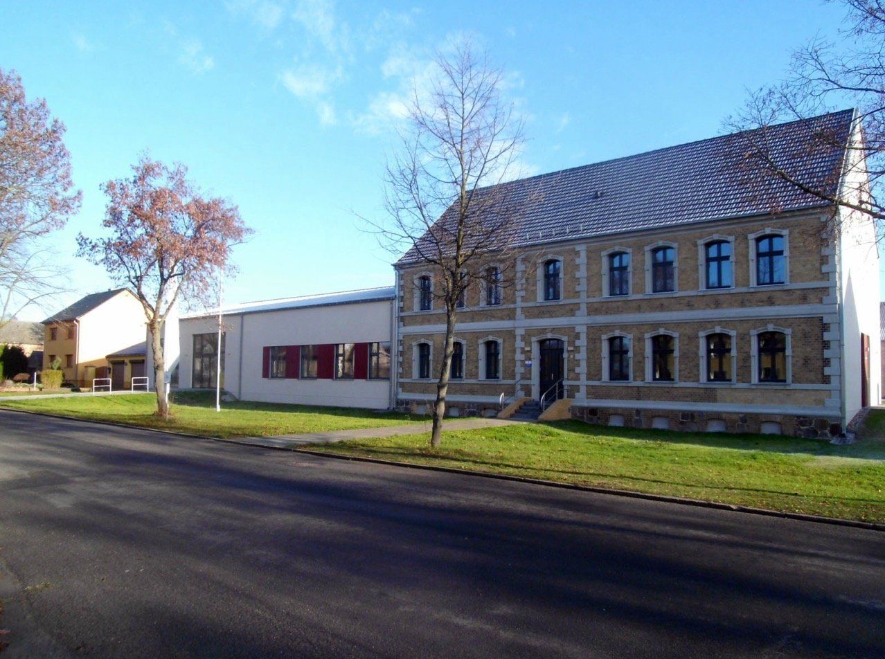 A large building with a red roof is next to a smaller building