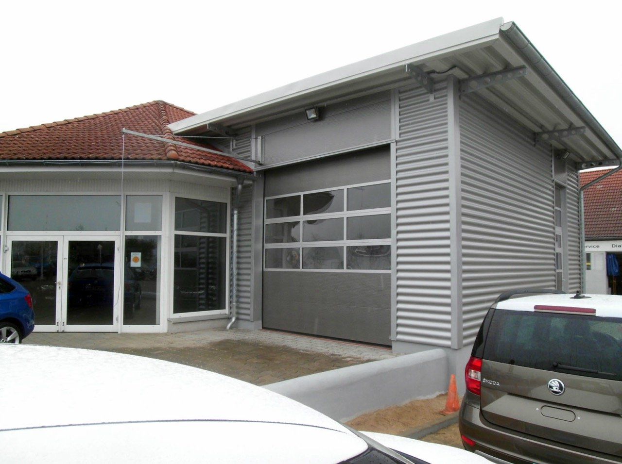 Two cars are parked in front of a building with a garage door