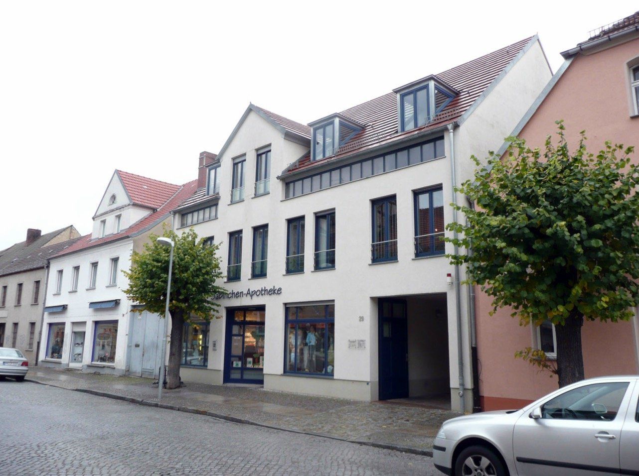 A car is parked in front of a white building