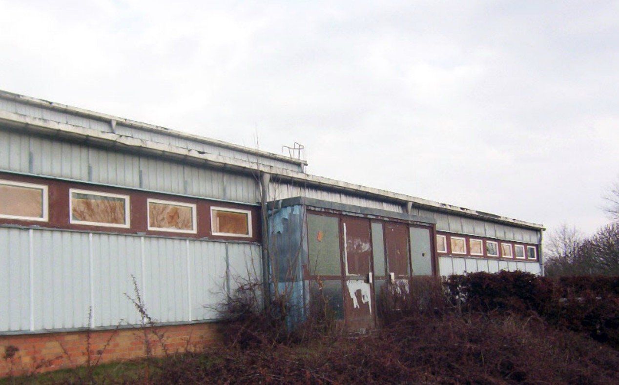 A large building with a lot of windows is sitting in the middle of a field.