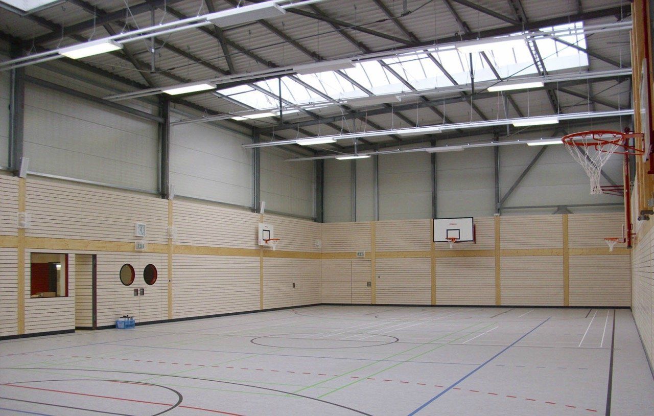 An empty gym with a basketball hoop in the middle