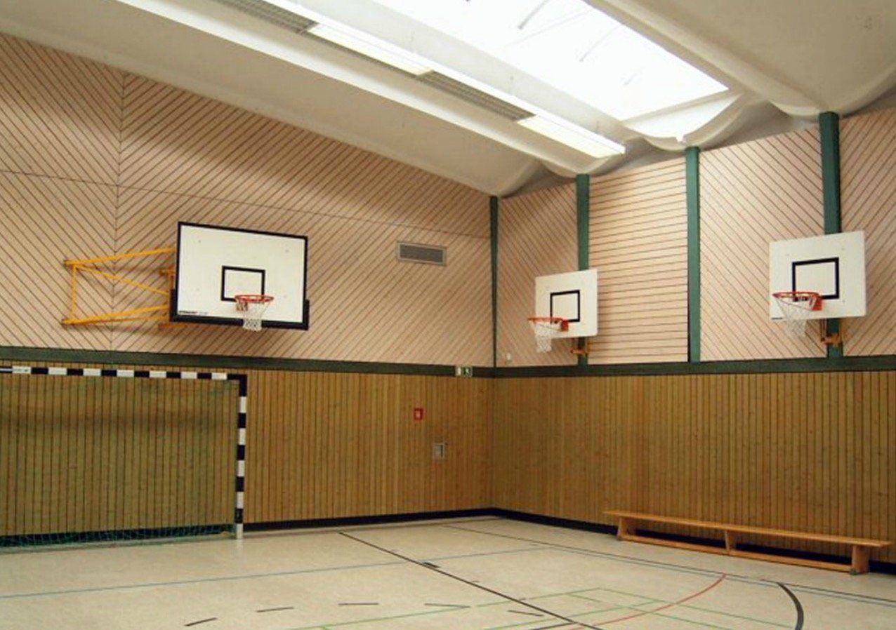 An empty basketball court with three basketball hoops on the wall
