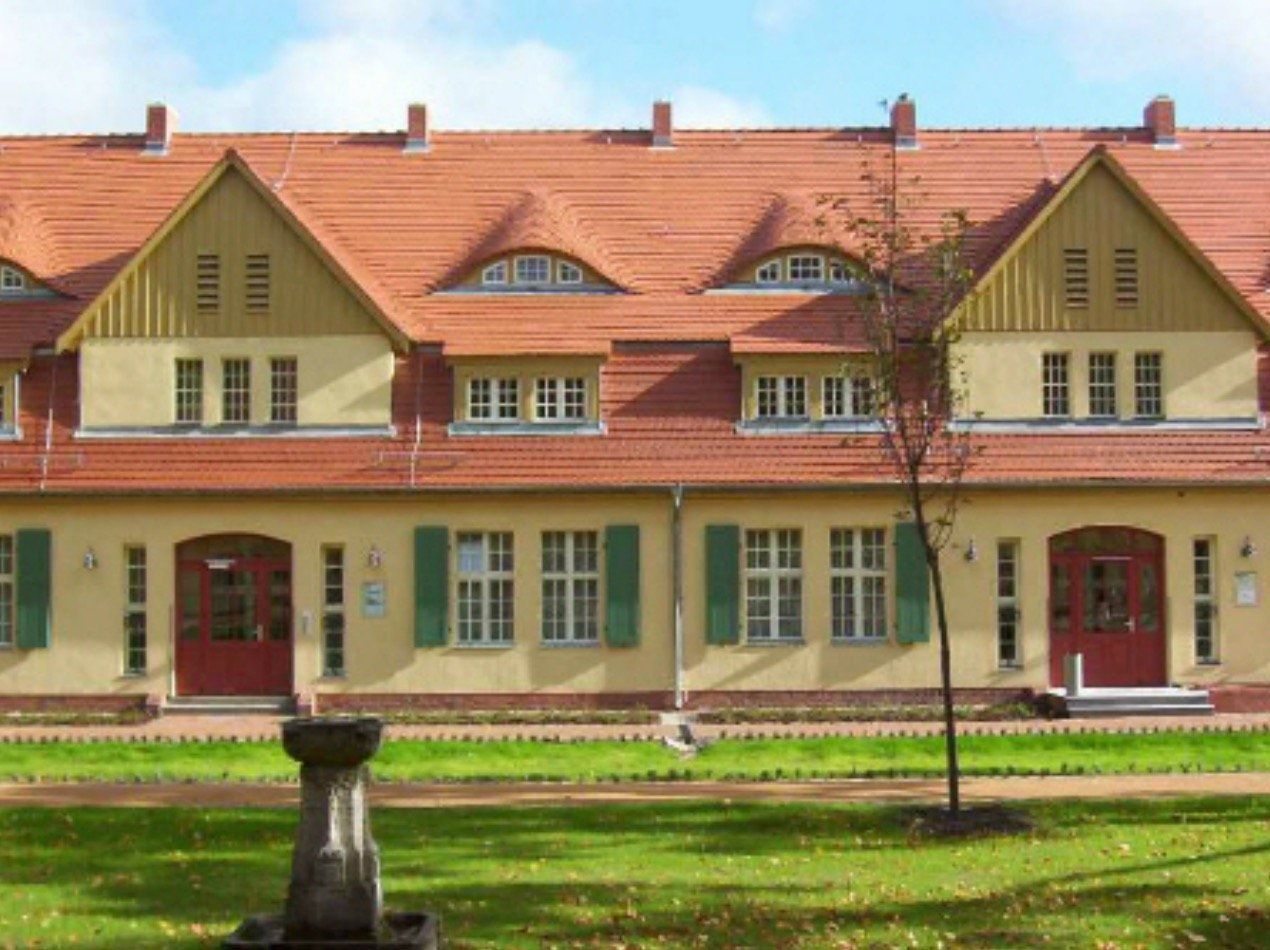 A large yellow building with a red roof and green shutters