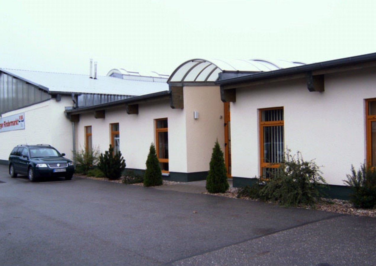 A black car is parked in front of a white building