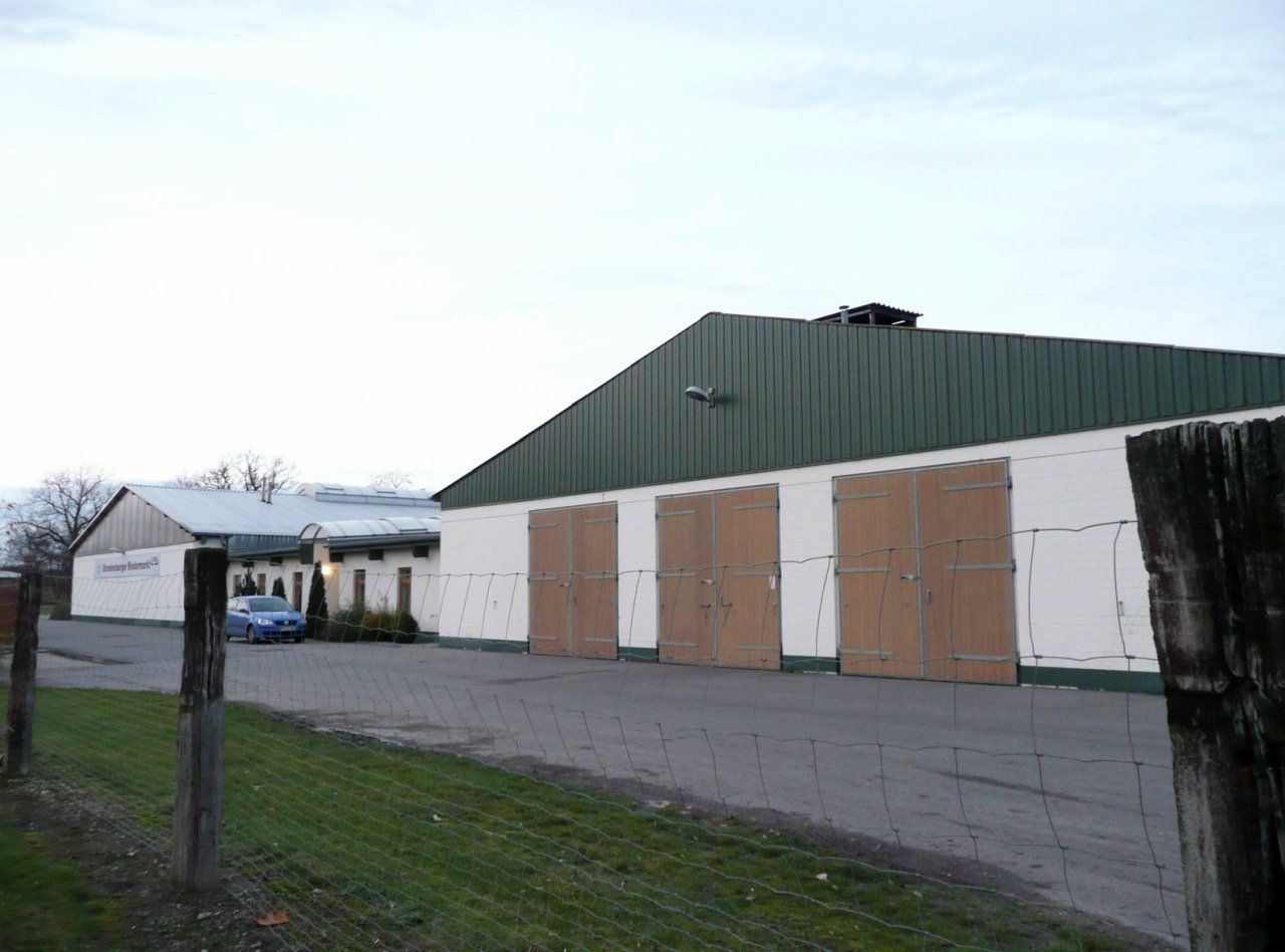 A large white building with a green roof and wooden doors