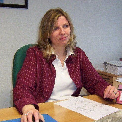 Eine Frau in einer rot gestreiften Jacke sitzt an einem Schreibtisch