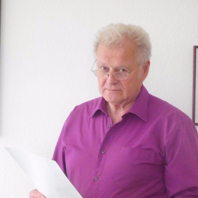 Ein Mann in einem lila Hemd hält ein Stück Papier