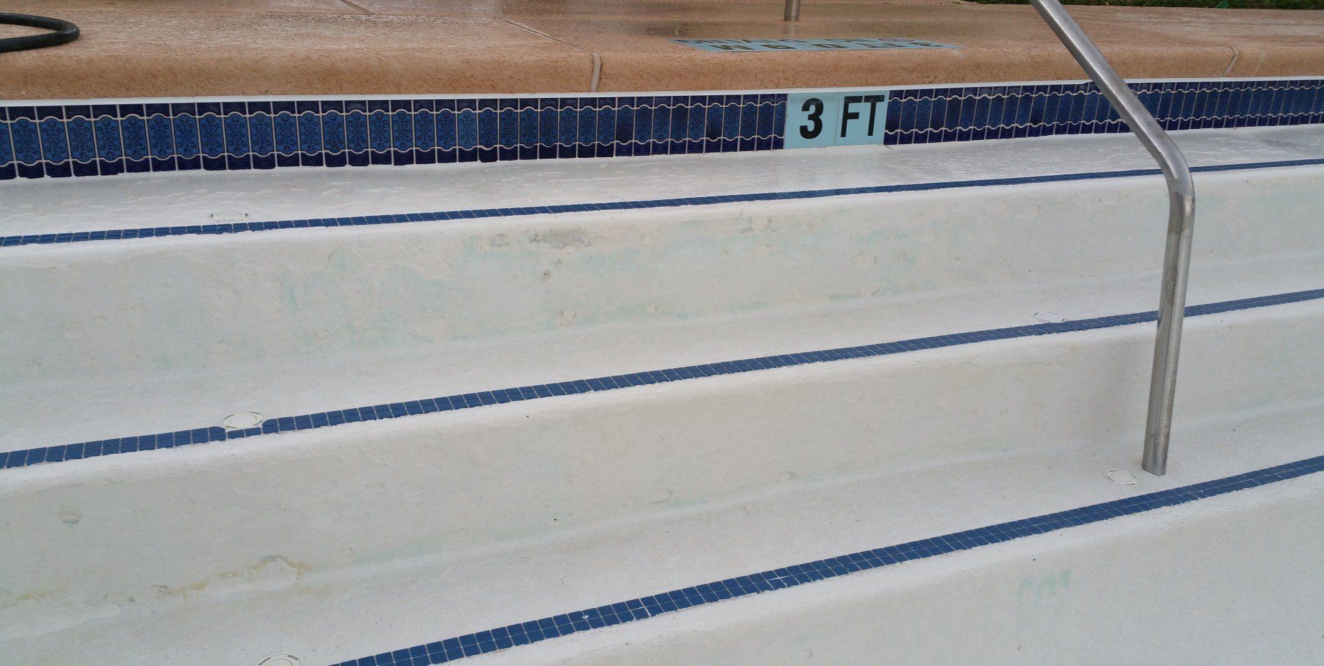 Indoor pool steps with blue lane markings and a 3-foot depth sign on the wall