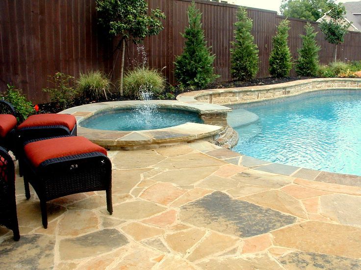 Backyard pool with stone patio, hot tub, and black lounge chairs with red cushions