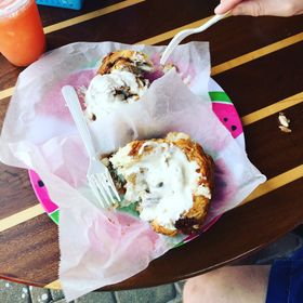 Cinnamon roll with white frosting on a watermelon plate, next to a juice.