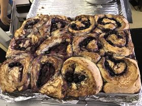 Tray of baked blueberry rolls. Swirled pastries with dark blue filling, golden brown crust.
