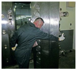A man in a black jacket is opening a large metal door