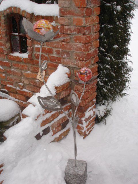 Eine Backsteinmauer mit Schnee darauf und einer Skulptur davor