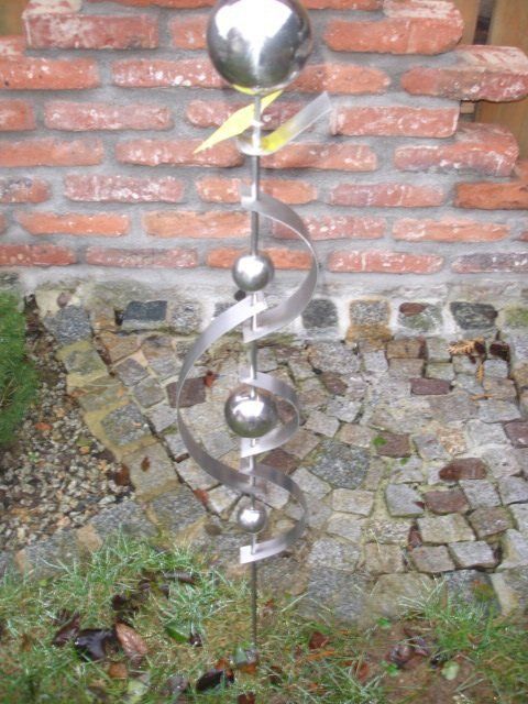 Eine Metallskulptur steht vor einer Backsteinmauer